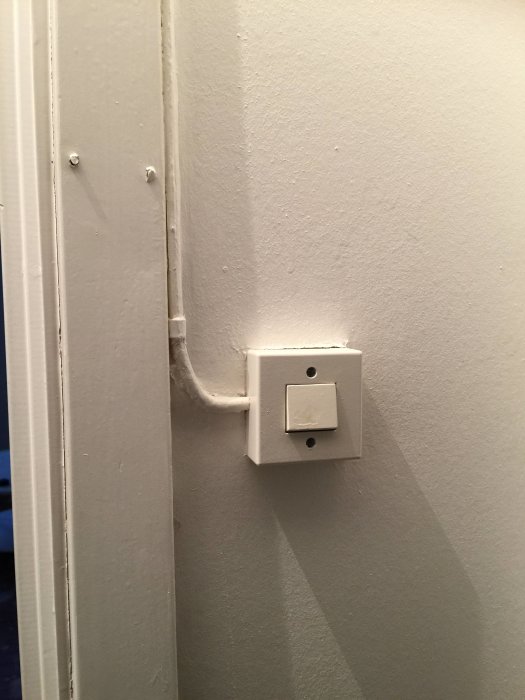 Elkabel spikad på dörrfoder och en fastskruvad strömbrytare på väggen.