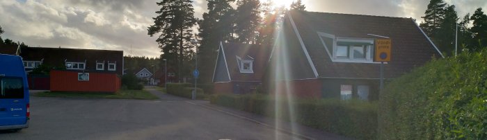 Gatuvy med blå buss, hus och skylten "vändplats", solen blänker i linsen.