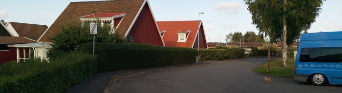 Panoramavy av en vändzon med ett blått fordon parkerat och röda hus i bakgrunden.