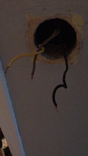 Öppning i tak med en gul kabel och en svart kabel som sticker ut, i en elinstallationssituation.