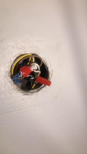 Blå kabel tillsammans med andra kablar i öppen vägguttagdosa.