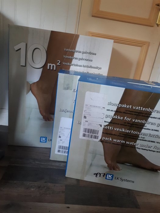 Förpackningar med vattenburen golvvärme på ett trägolv inne i ett hus.