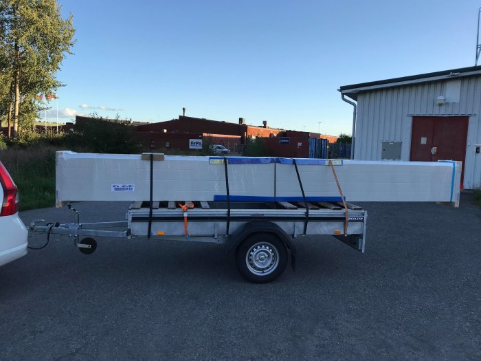 Hörmann LPU42 garageport i RAL 8004 på släpvagn parkerad utomhus.