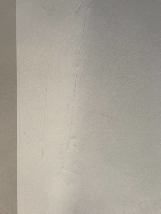 Sprickor i vitt tak där målning och spackling utförts efter borttagning av limfärg.