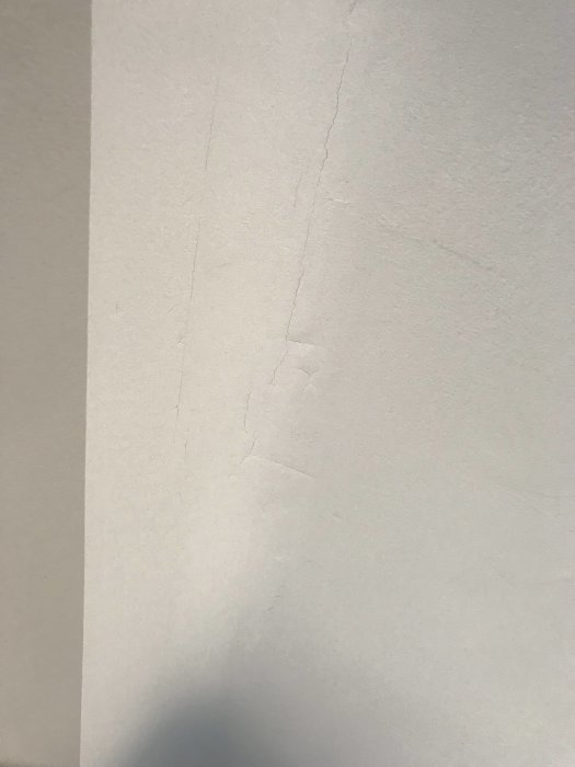 Vitmålat tak med synliga sprickor längs en böjd del, vilket indikerar en möjlig problematik i underarbetet eller material.