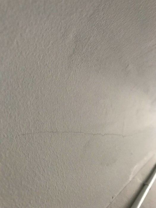 Sprickor i nymålat tak där böjning finns, visar defekter i målararbetet.