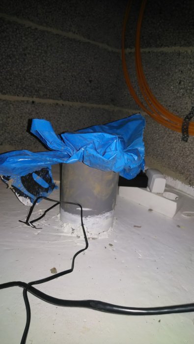 110-rör som sticker upp genom betongplatta med blå plast överst och kablar i förgrunden.