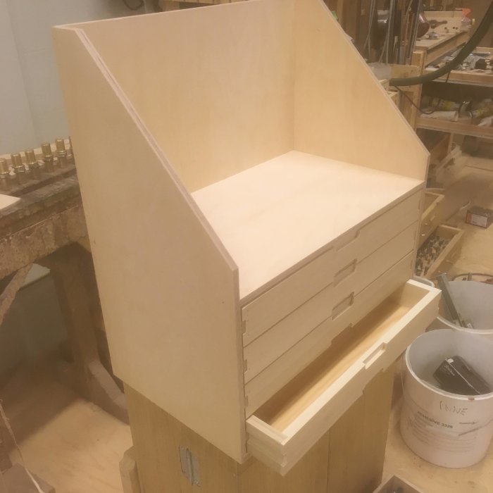 Träkonstruktion med flera lådor i en verkstad, utformad för att anpassas till en bilbaklucka.