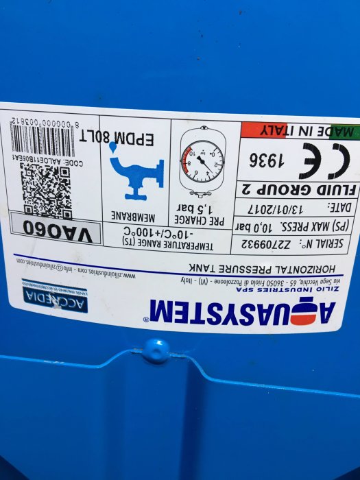 Märkesetikett på en blå trycktank med tekniska detaljer, en QR-kod och manometer som visar trycket.