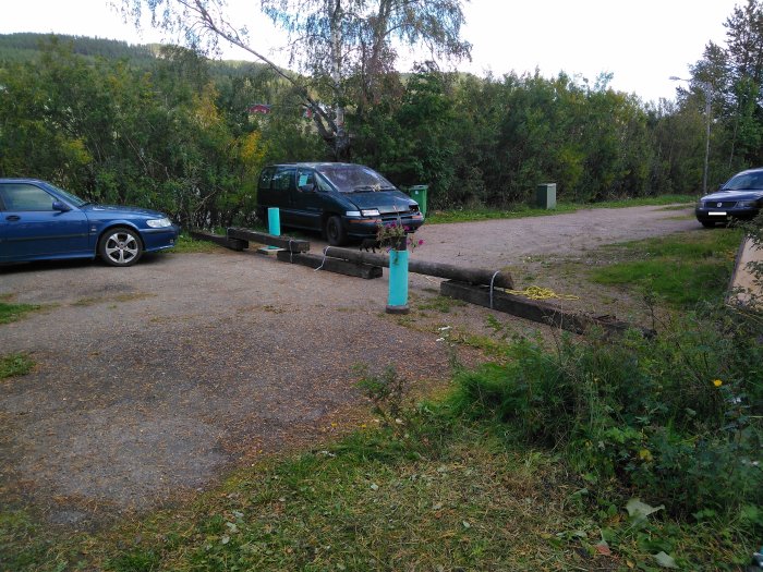 Träd och brädor blockerar del av gårdsplanen med bilar runtom, indikation på gränstvist.