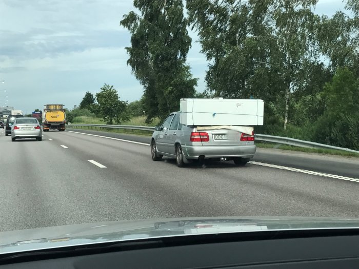 Bil på E20 med överlastad bagagebox nära Göteborg.
