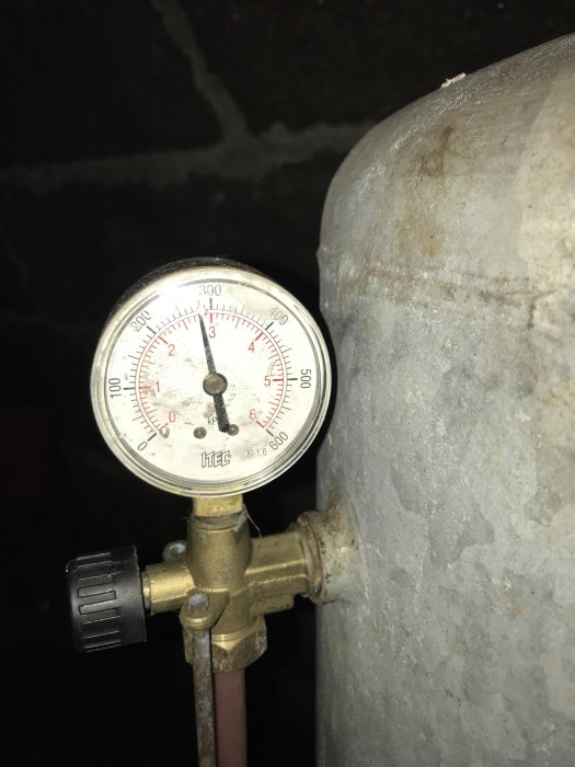 Manometer på hydrofor med visare som visar trycket, monterad på ett vattenrör.