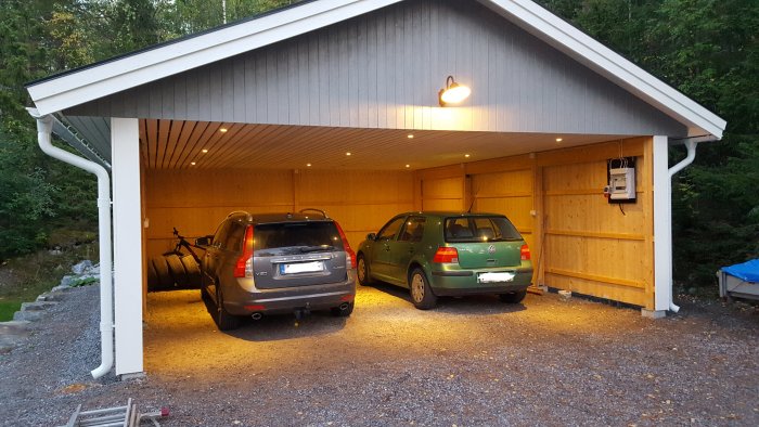 Carport med ny installation av belysning och rörelsesensor, två parkerade bilar.