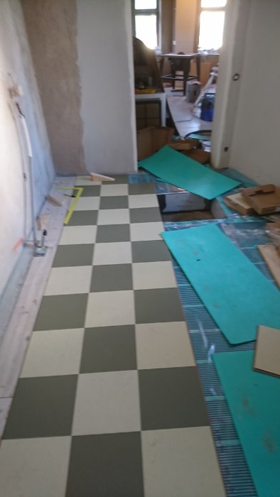 Installation av golvärme och rutigt linoleumgolv i pågående köksrenovering.