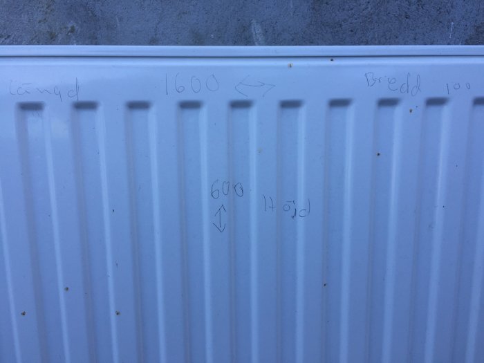 Vit radiator med handskrivna mått och prisnoteringar på framsidan.