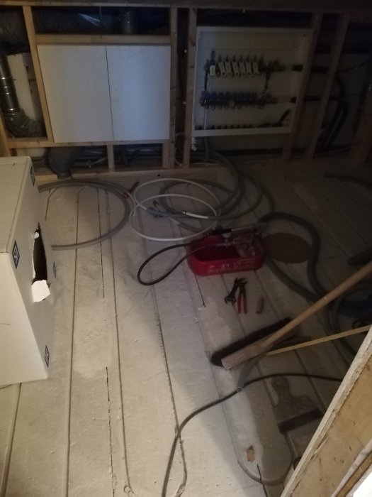 Inredning av ett pågående byggprojekt med synliga rörledningar och elinstallationer.