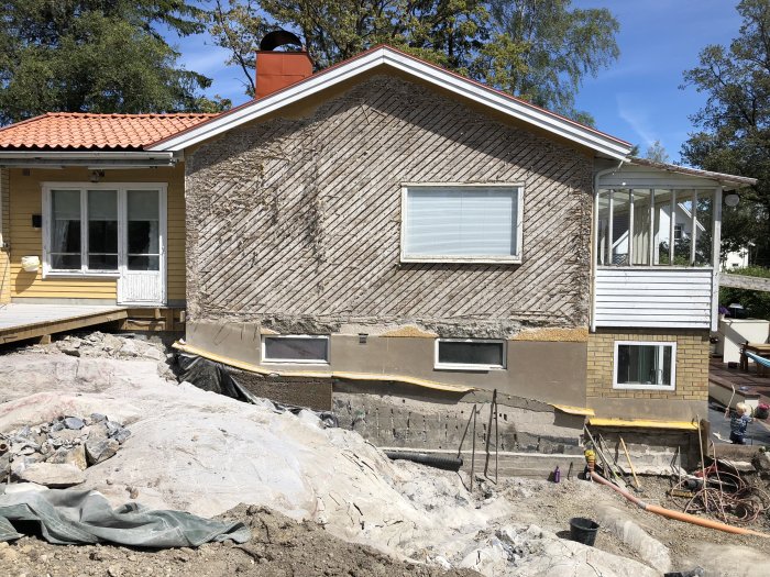 Hus under renovering med exponerad grund och grävarbete runtomkring.