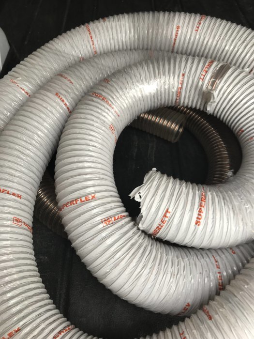 Vitt, spiralformat slang av märket Superflex, inköpt för användning till spånsug.