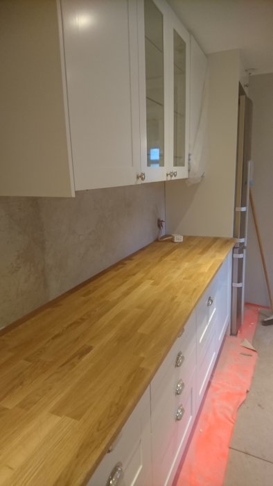 Nyinstallerad träbänkskiva och omonterad kakelvägg i ett kök under renovering.