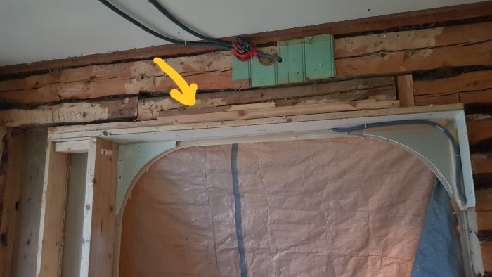 Träkonstruktion med pil som visar på en balk som ska tas bort, med en stående stock bultad i väggen.