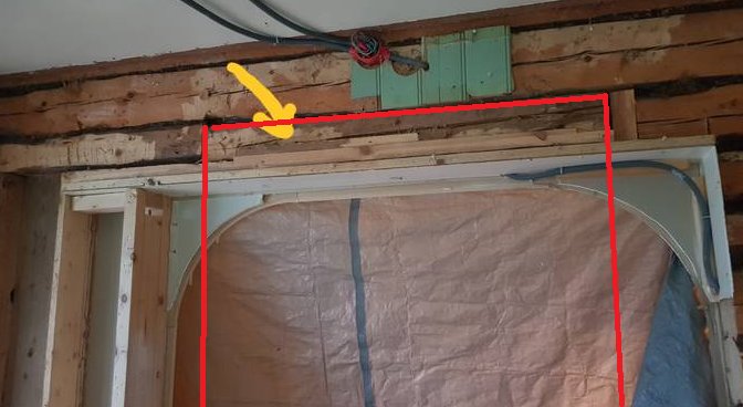 Renoverad vägg med en bred dörröppning och synliga stockar, röd och gul markering indikerar konstruktionsdetaljer.