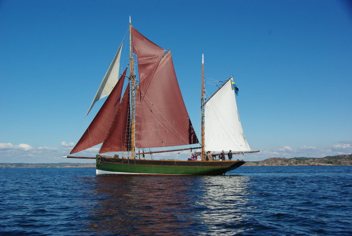 En klassisk segelbåt med röda och vita segel på öppet vatten.