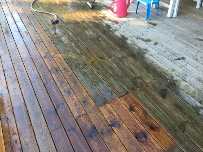 Trätrall med en renad yta jämfört med det smutsiga, algtäckta området, slang och vattenkanna syns.