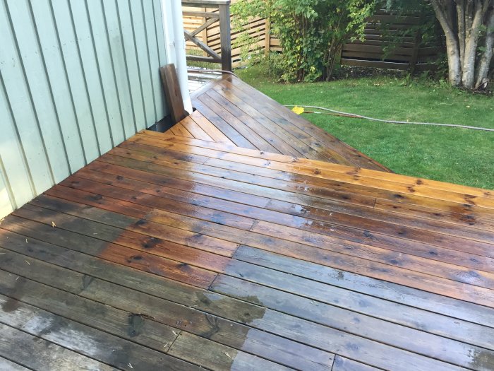 Trädäck delvis rengjort med tvättmedel, synlig skillnad mellan behandlade och obehandlade plankor.