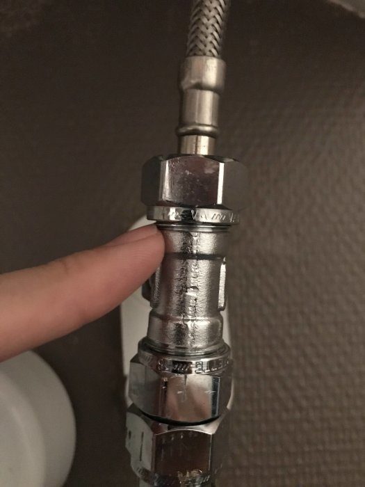 Finger pekar på gängstarten på ett rörkopplingsstycke där kallvattenanslutningen är.