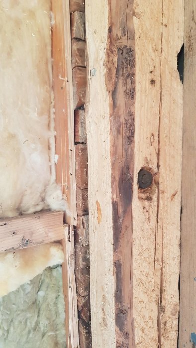 Delvis exponerad isolering och träreglar på en vägg under renovering.