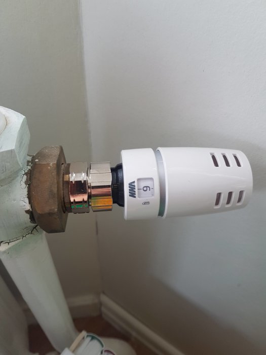 Ny termostat monterad på radiator med adapter synlig, står på inställning mellan 3 och 4.