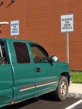 Grön pickup parkerad vid skylt som säger "Reserved for green vehicles".