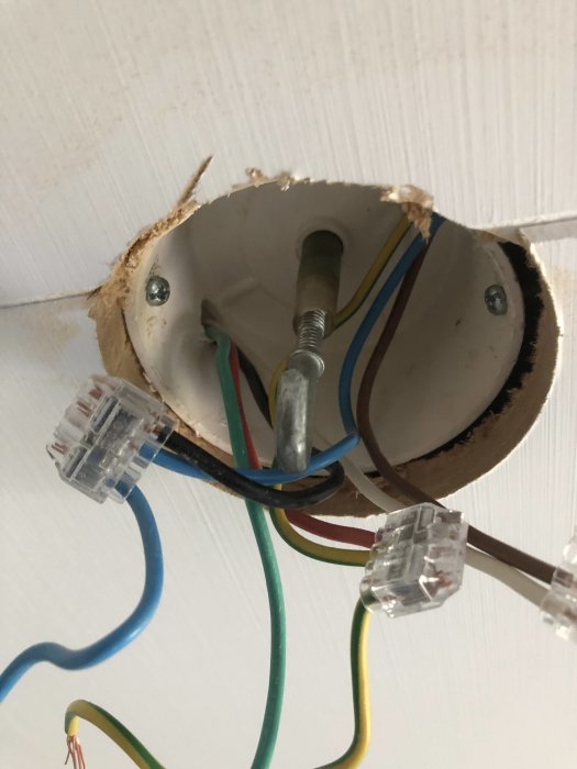 Takdosöppning med för kort centrumbult och synliga elledningar i ett nyinstallerat huntonit-tak.