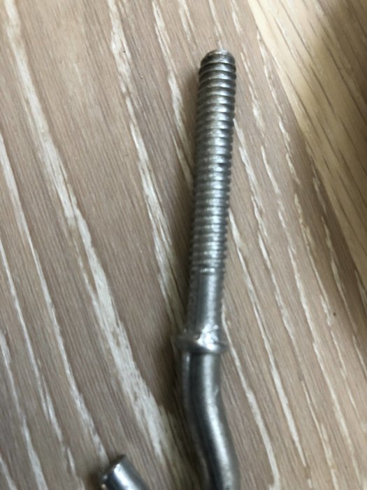 En för kort centrumbult som används för att fästa lamputtag i tak mot en träbeklädnad.