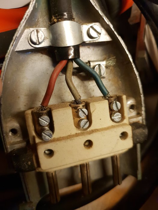 Närbild av en elektrisk anslutning i en äldre byggsåg med kopplade kablar i färger röd, svart och grön/blå.