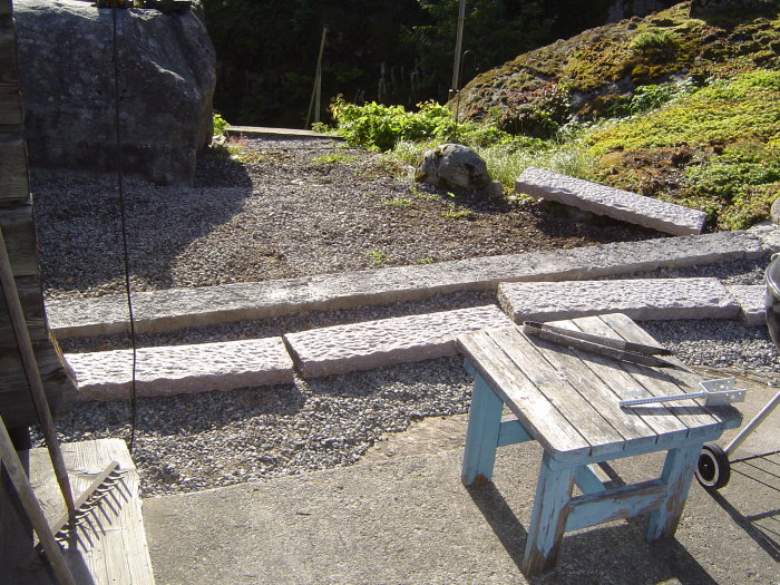 Nyupparbetad trädgårdstrappa av sten med grusväg och trädgårdsverktyg, belägen på bergsterräng.