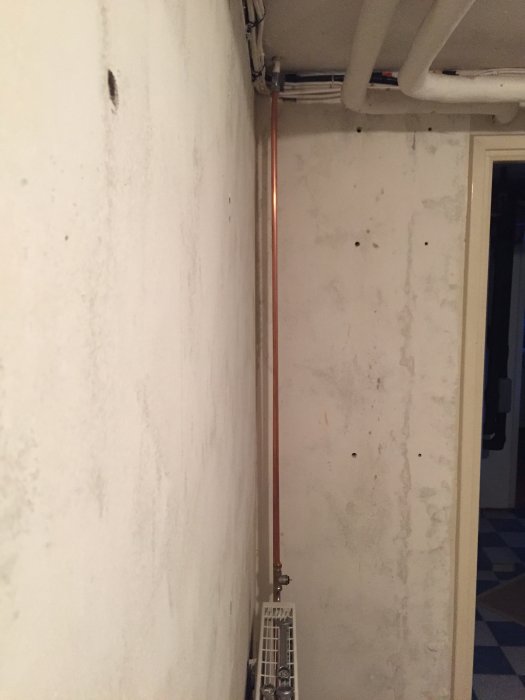 Nyinstallerad radiator med väl böjda kopparledningar mot en vit vägg i renoveringsprojekt.