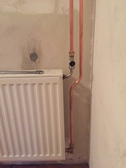 Nyinstallerad radiator med kopparledningar och S-böj i ett renoveringsprojekt.