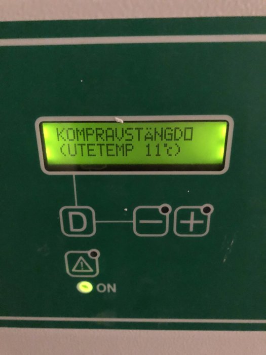 Display på en värmepump som visar "KOMPR AVSTÄNGD" och "UTETEMP 11°C" med indikatorn ON lyser grönt.