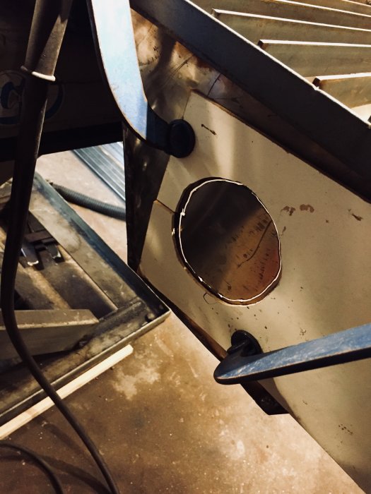 Handgjord böjd metallstos för sugfläkt installerad på ett svetsbord i en verkstad.