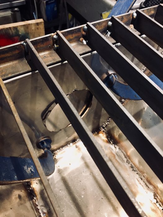 Metalltråg med sugfläktsslang ansluten under ett metallgaller, använd vid svetsning och slipning.