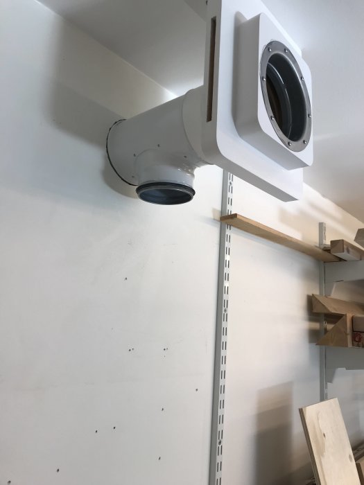 Vit ventilationskanal på vägg med 90 graders böj vid tak, i ett renoveringsprojekt.