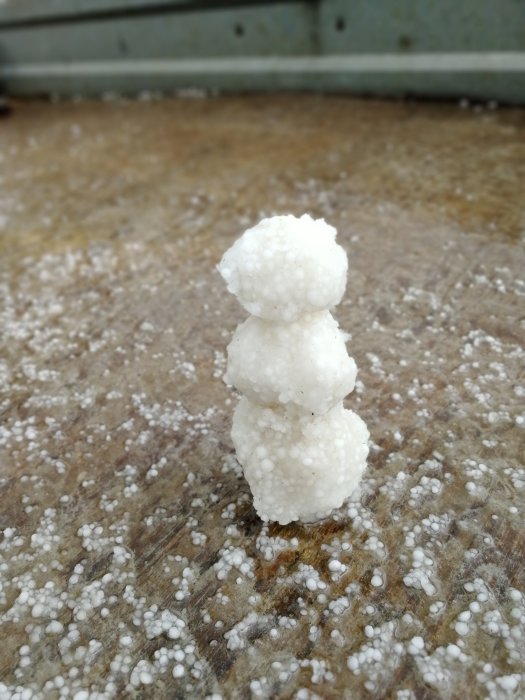 Liten snögubbe av hagel på brun bakgrund.