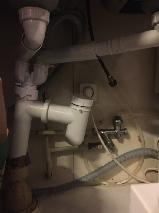 Vattenlås och rör under köksskåp, ser ovanligt ut med avstickare, potentiell orsak till dålig lukt.