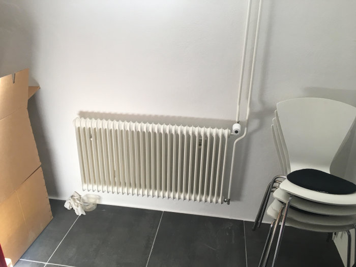 Vattenburen radiator i ett rum, inkopplad i ett tvårörssystem, med synlig termostat.