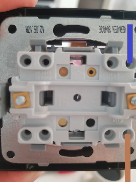 Närkontakt av en elektrisk vägguttagsbaksida utan täckplatta med synliga ledningsanslutningar.