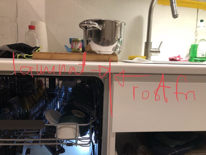 Diskmaskin öppen under köksbänk med tillfälliga laminatskivor, markerade för utbyte till laminat och rostfri yta.