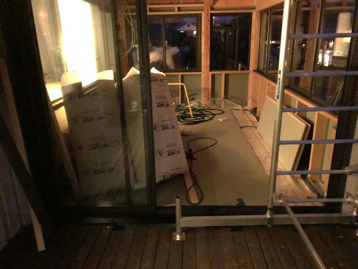 Renoveringsarbete i ett uterum med isoleringsmaterial, elinstallationer i golvet och nästan fullständigt lagt golvspån.