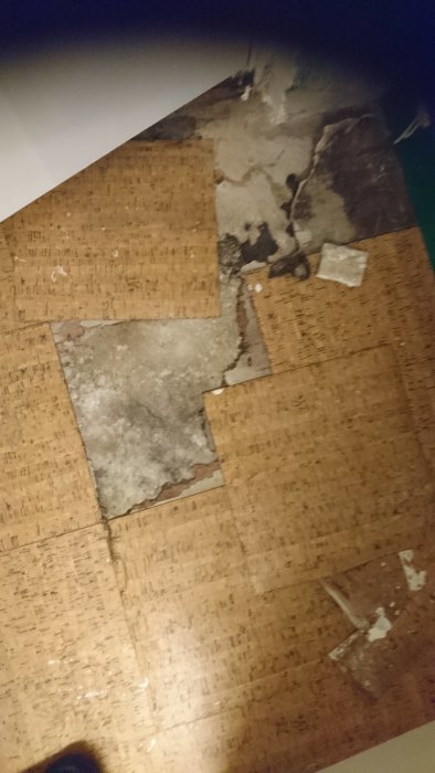 Gamla skadade fyrkantiga plastmattor på betong och plywood med löst lim.