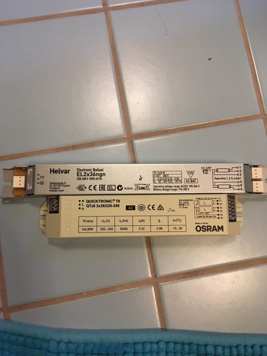 Helvar och Osram elektroniska drivdon bredvid varandra på ett kaklat golv.